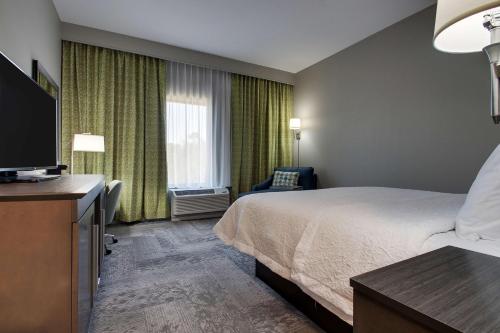 a hotel room with a bed and a flat screen tv at Hampton Inn & Suites By Hilton Knightdale Raleigh in Raleigh
