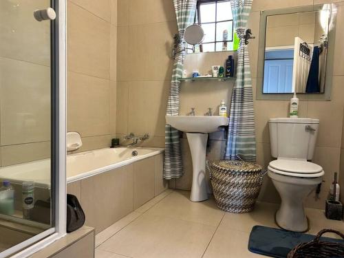 a bathroom with a sink and a toilet and a bath tub at Big Fish Seaside Cottage, sleeps 10 Guests in 5 Bedrooms in Port Edward