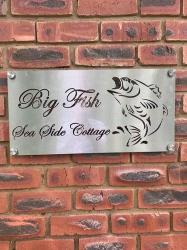 a sign on a brick wall with a bird on it at Big Fish Seaside Cottage, Sleeps 10 Guests in 5 Bedrooms in Port Edward