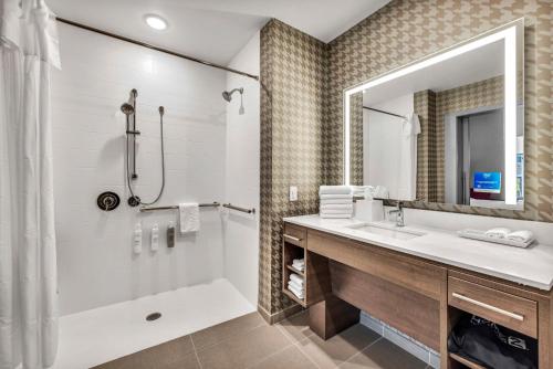 a bathroom with a tub and a sink and a mirror at Home2 Suites By Hilton Raleigh State Arena in Raleigh