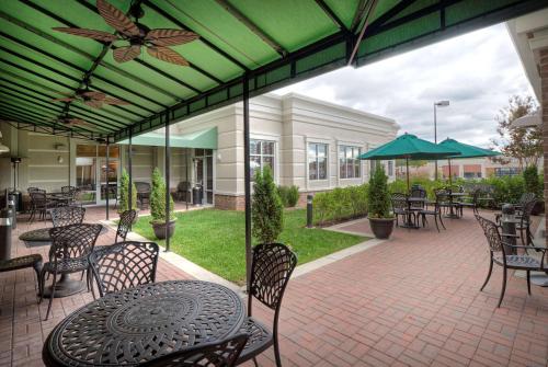 an outdoor patio with tables and chairs and an umbrella at Hilton Garden Inn Durham Southpoint in Durham