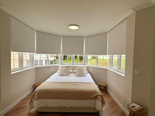 a bedroom with a large bed with windows at El Faro de la Barquera in San Vicente de la Barquera