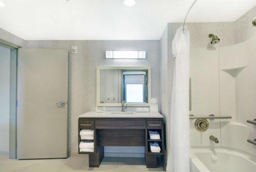 a bathroom with a sink and a mirror and a tub at Home2 Suites By Hilton Raleigh Durham Airport RTP in Durham