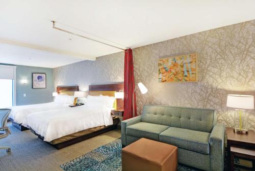 a hotel room with a bed and a couch at Home2 Suites By Hilton Raleigh Durham Airport RTP in Durham