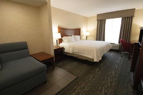 Hampton Inn & Suites Richmond/Virginia Center في ريتشموند: غرفه فندقيه بسرير وكرسي