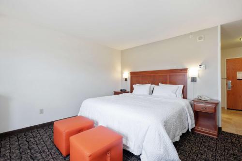 a hotel room with a large bed and an orange stool at Hampton Inn & Suites Rockland in Thomaston