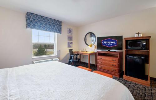 a hotel room with a bed and a tv and a desk at Hampton Inn & Suites Rockland in Thomaston