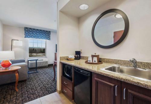 a kitchen with a sink and a living room at Hampton Inn & Suites Rockland in Thomaston