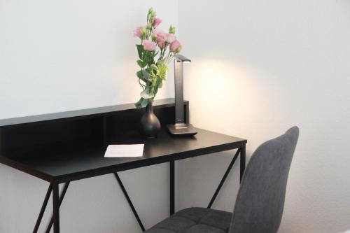 un escritorio con un jarrón de flores y una silla en DREAMSPACE l Kingsize Bett + FREE coffee & cookies, en Darmstadt