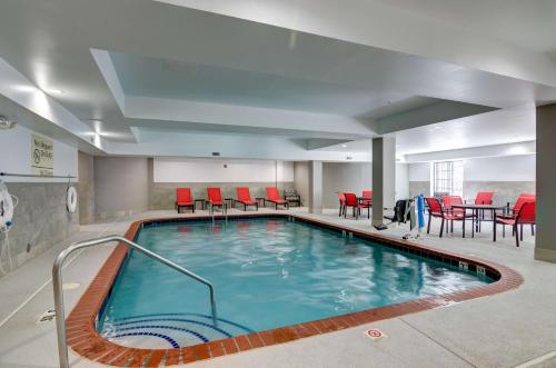 a swimming pool with red chairs and a table at Hampton Inn Salem in Salem