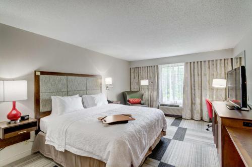 a hotel room with a bed and a flat screen tv at Hampton Inn Salem in Salem