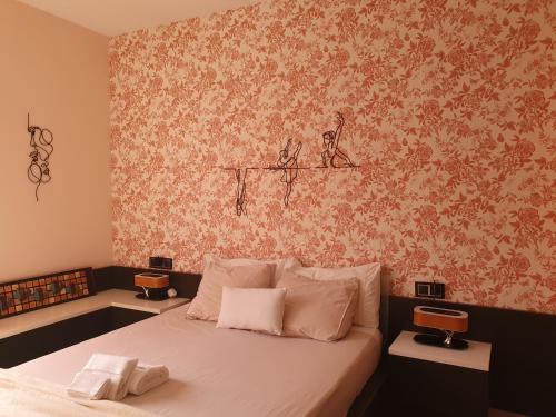 1 dormitorio con cama y pared con papel pintado con motivos florales en El Arroyo, en Sevilla