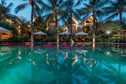 a swimming pool with palm trees and a hotel at Coco Island Villa & Hotel Ninh Bình in Ninh Binh