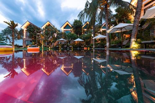 einen Pool in einem Resort mit Sonnenschirmen und Palmen in der Unterkunft Coco Island Resort Ninh Binh in Ninh Bình