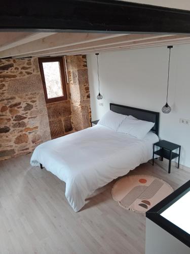 Un dormitorio con una gran cama blanca con ventana. en La Gavina, en Beáriz