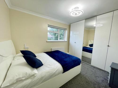 a bedroom with a bed with blue pillows and a mirror at New Luxury Modern House near Airport Free Parking in Luton