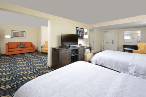 a hotel room with two beds and a flat screen tv at Hampton Inn Roxboro in Roxboro