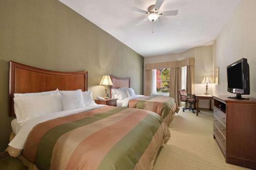 a hotel room with two beds and a flat screen tv at Homewood Suites by Hilton Rochester - Victor in Victor