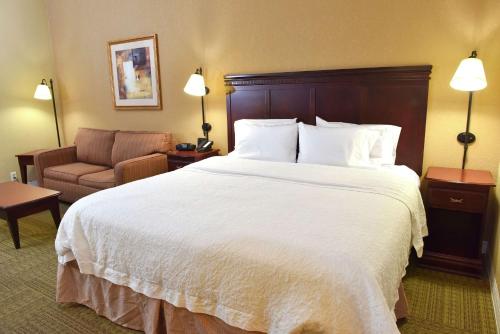 a hotel room with a large bed and a chair at Hampton Inn Ruston in Ruston