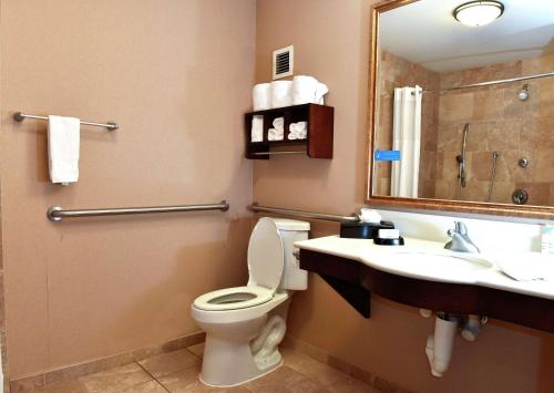 a bathroom with a toilet and a sink and a mirror at Hampton Inn Ruston in Ruston