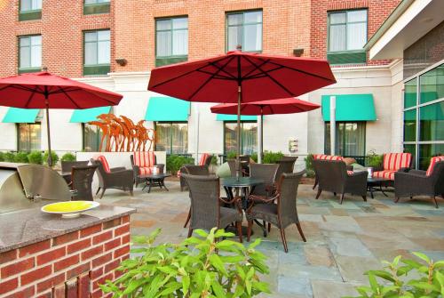 un patio con sedie e tavoli con ombrelloni rossi di Homewood Suites by Hilton Rockville- Gaithersburg a Rockville