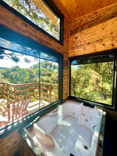 a bath tub in a room with two windows at Flor da serra in Urubici