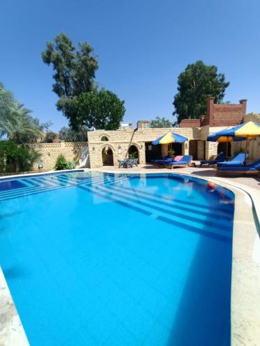 a large swimming pool with a house in the background at palm shadow resort in Tunis