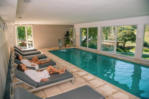 two people laying on lounge chairs in front of a swimming pool at Hostería & Spa De La Cascada in Tandil