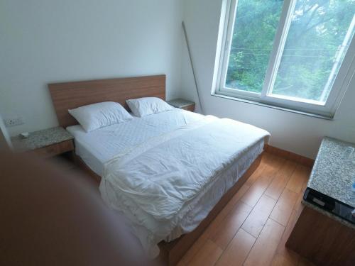 una camera da letto con un letto con lenzuola bianche e una finestra di OLIVIA HOME STAY a Dehradun