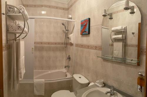 a bathroom with a toilet and a tub and a sink at Casa Do Gerardo in Nazaré
