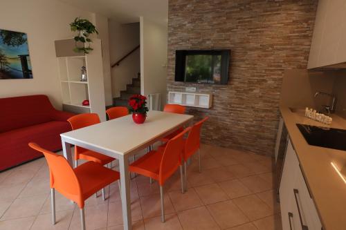 a kitchen and living room with a white table and orange chairs at Villaggio Mare Blu in Bibione