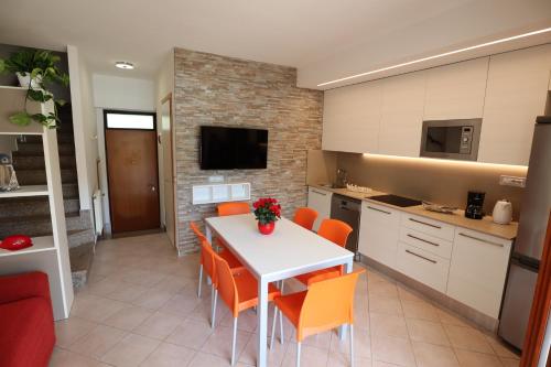 a kitchen with a white table and orange chairs at Villaggio Mare Blu in Bibione