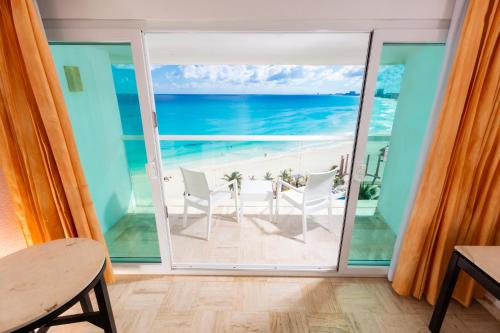 a room with a balcony with a view of the ocean at Krystal Cancun in Cancún