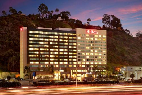ein beleuchtetes Hotelgebäude mit einem Hügel im Hintergrund in der Unterkunft Hilton San Diego Mission Valley in San Diego