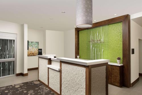 a lobby with a counter with a green wall at Hilton Garden Inn San Antonio Airport South in San Antonio