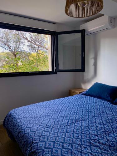 une chambre avec un lit bleu et une fenêtre dans l'établissement Appartement au calme, Calanque des Figuières, à Ensuès-la-Redonne
