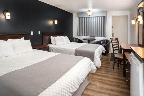 Cette chambre d'hôtel comprend deux lits, une table et des chaises. dans l'établissement Hôtel Marineau Centre, à La Tuque
