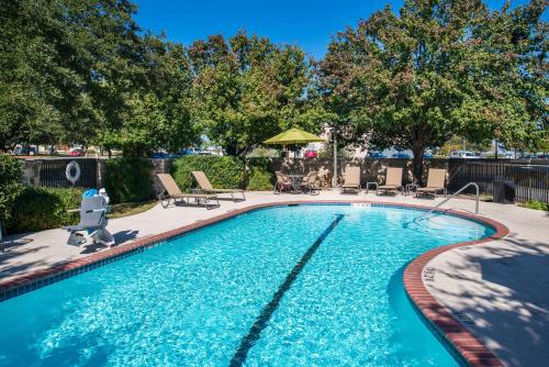 una gran piscina con sillas y árboles en un patio en Hampton Inn San Antonio Stone Oak, en San Antonio