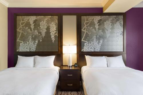 two beds in a hotel room with purple walls at DoubleTree by Hilton Historic Savannah in Savannah