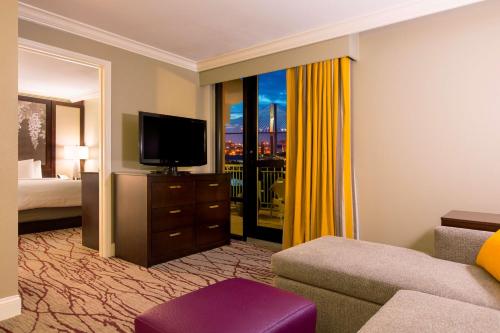 a living room with a television and a room with a bed at DoubleTree by Hilton Historic Savannah in Savannah