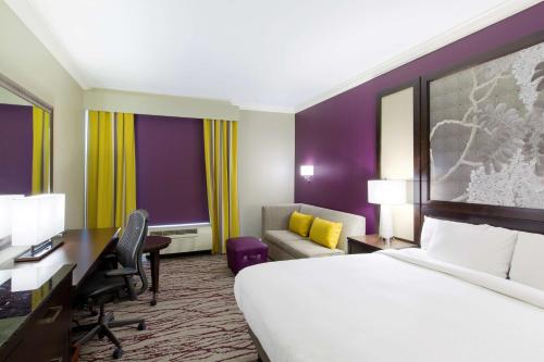 a hotel room with a bed and a desk and a couch at DoubleTree by Hilton Historic Savannah in Savannah