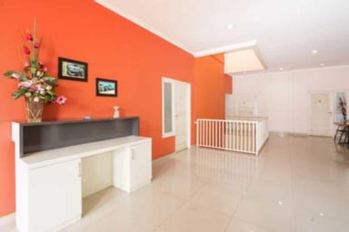 a living room with orange walls and a vase of flowers at Semampir Residence By Occupied in Surabaya