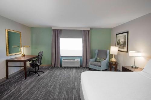 a hotel room with a bed and a desk and a window at Hilton Garden Inn South Bend in South Bend