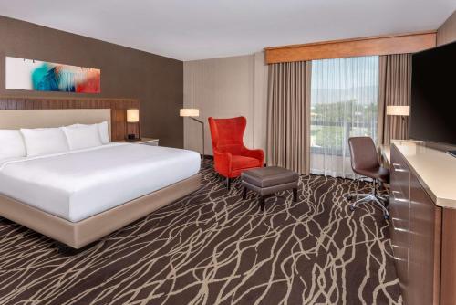 a hotel room with a bed and a red chair at DoubleTree by Hilton San Bernardino in San Bernardino