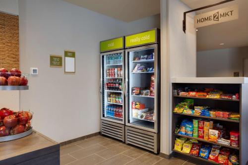 a grocery store aisle with an open refrigerator at Home2 Suites By Hilton Lewes Rehoboth Beach in Lewes