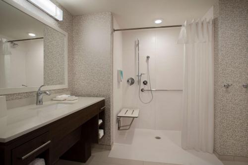 ein Badezimmer mit einer Dusche, einem Waschbecken und einer Badewanne in der Unterkunft Home2 Suites By Hilton Lewes Rehoboth Beach in Lewes