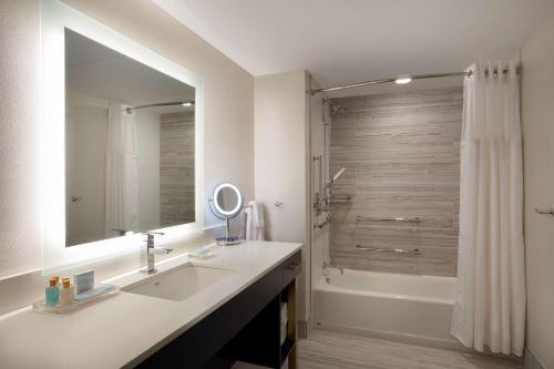 La salle de bains est pourvue d'un lavabo et d'une douche avec un miroir. dans l'établissement Fenwick Shores, Tapestry Collection by Hilton, à Fenwick Island