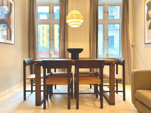 a dining room table and chairs in a room with windows at Amazing Apartment in Urban Neighborhood in Copenhagen
