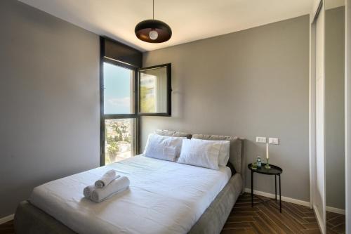a bedroom with a large white bed with a window at Stunning 2BR Apartment with Balcony and Ocean View in the Heart of Haifa by Sea N' Rent in Haifa