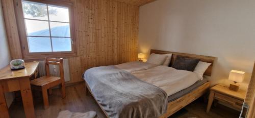Schlafzimmer mit einem Bett, einem Schreibtisch und einem Fenster in der Unterkunft Narcisse 14 in Champoussin